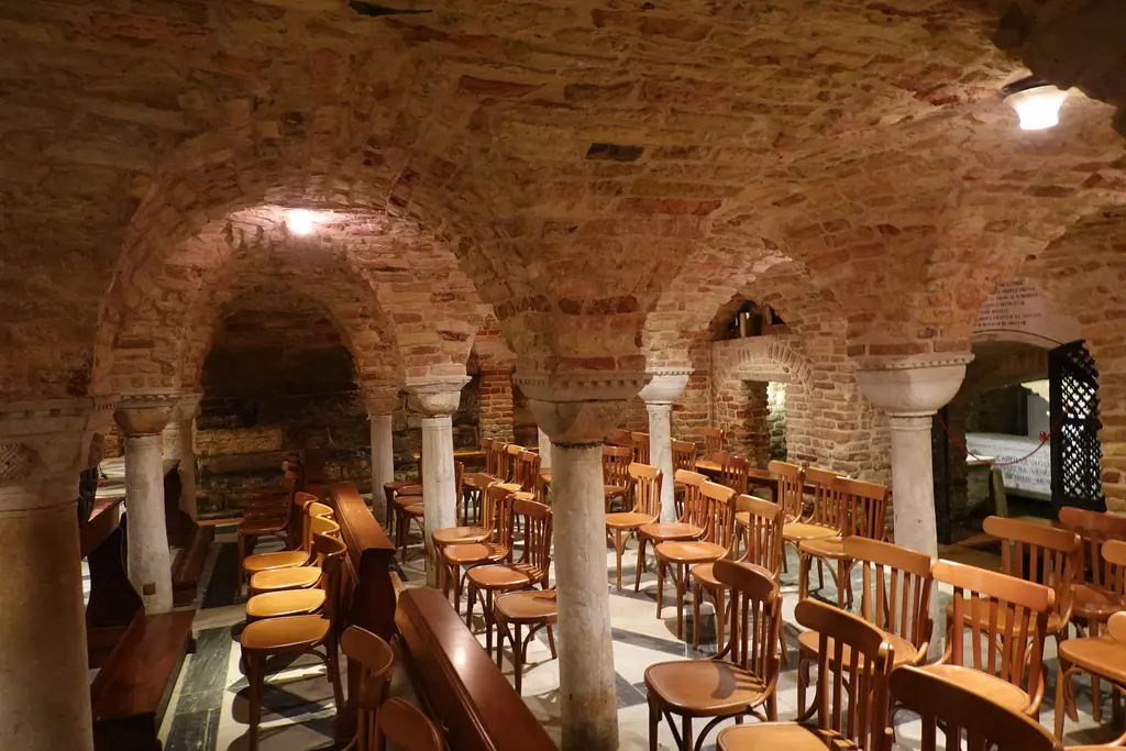 The crypt of St Mark’s: low brick vaults on small columns, with rows of wooden chairs