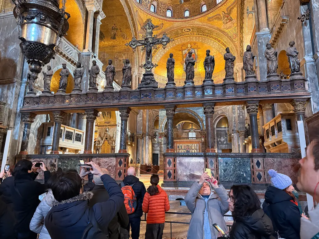 Visitors photographing the marble iconostasis, with its row of statues and the great cross