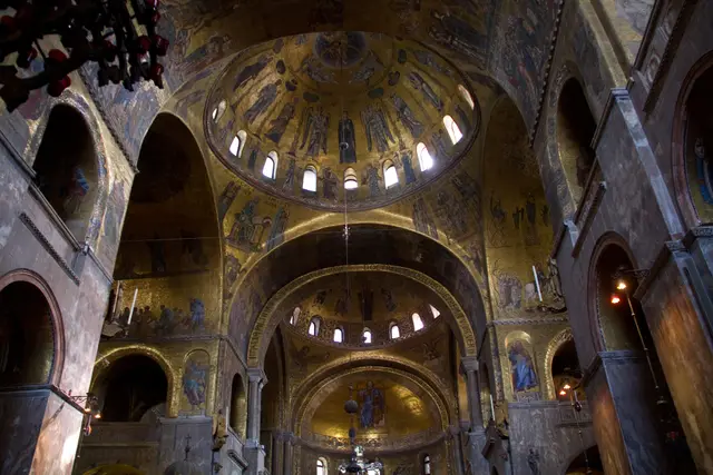 Arches and domes covered in gold mosaic, seen from below inside St Mark’s