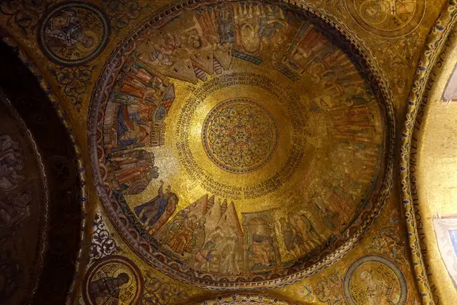 A gold mosaic dome inside St Mark’s Basilica, its figures and Latin inscription circling a star-shaped centre